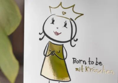 Abbildung eines Mädchens mit Krone und goldenem Kleid auf einer Karte. Der Text lautet „Born to be mit Krönchen.“.