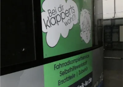 Auf einem Stadtbus ist die Werbung für einen Fahrradservice zu sehen. In einer Sprechblase mit dem Text „Bei dir klappert’s wohl?“ sind eine Telefonnummer und die URL einer Website zu sehen.